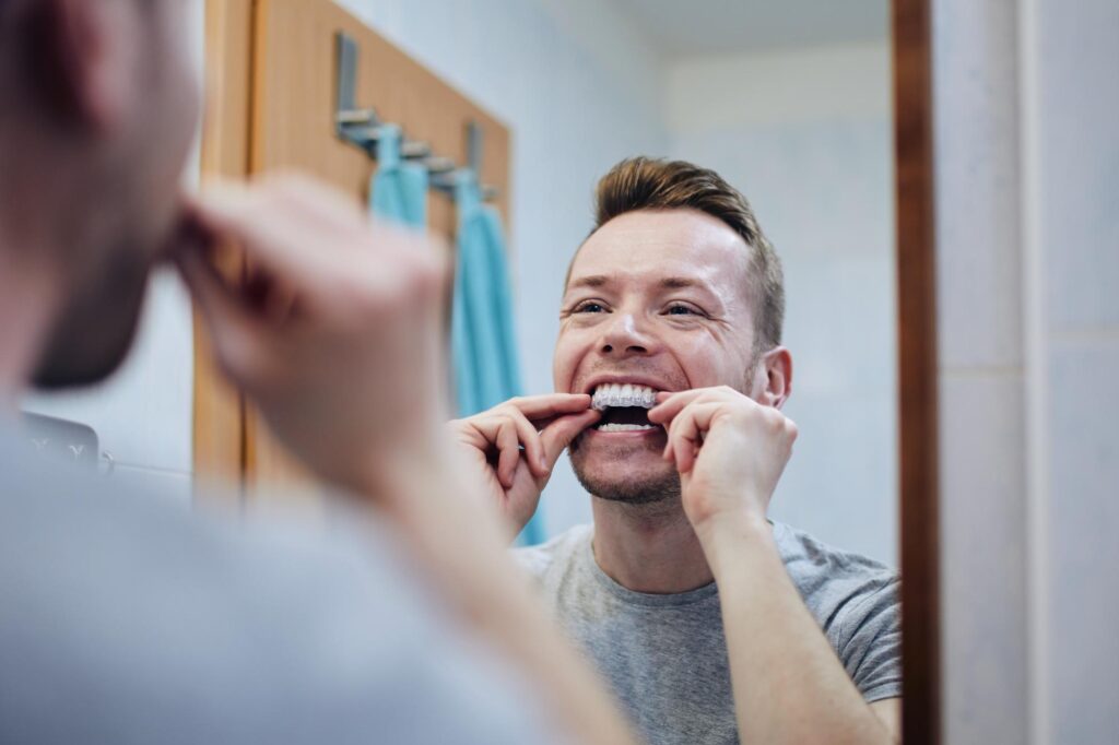 Two people flossing in front of a bathroom mirror