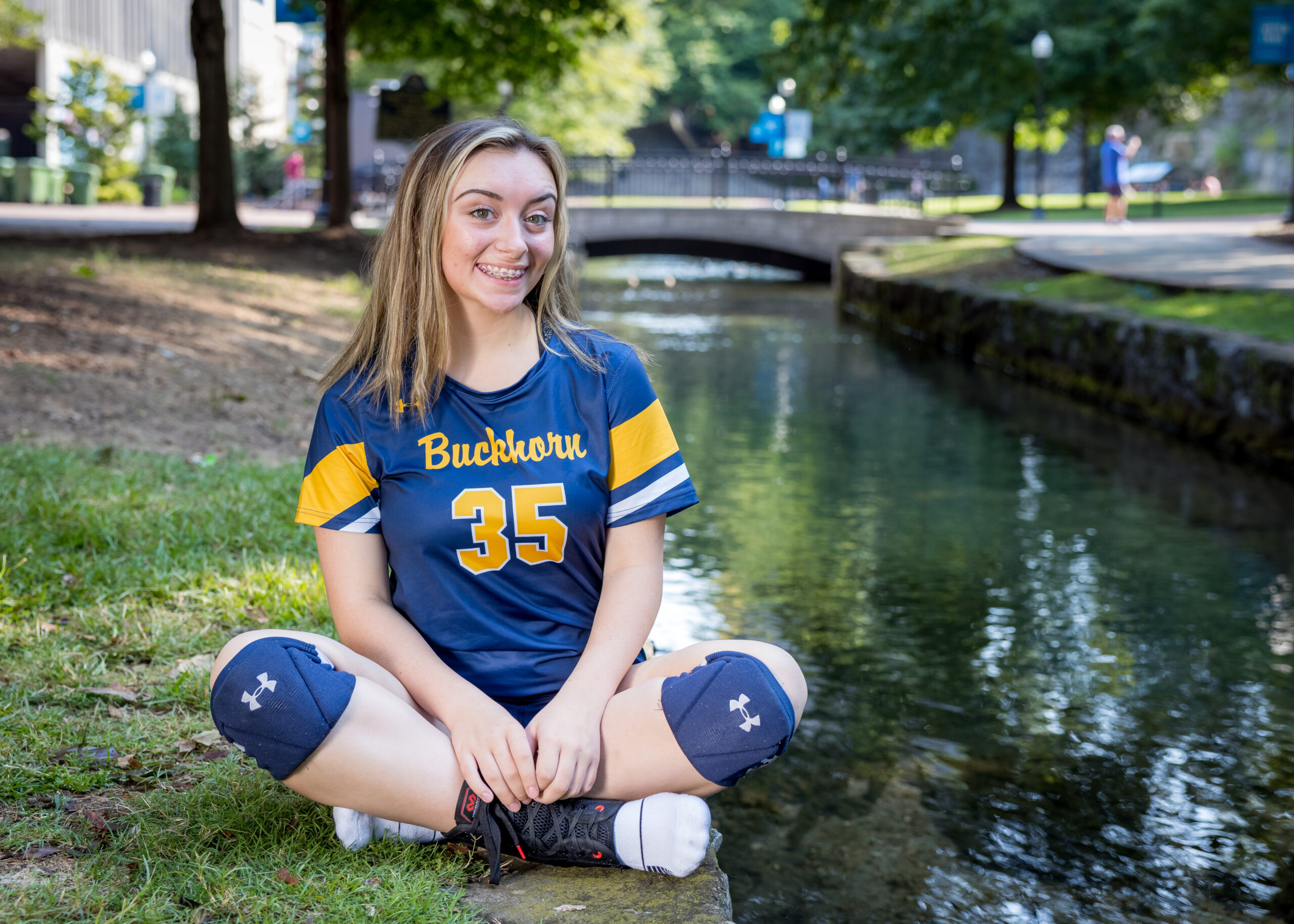 Limbaugh Orthodontics patient in her school jersey sitting beside a creek