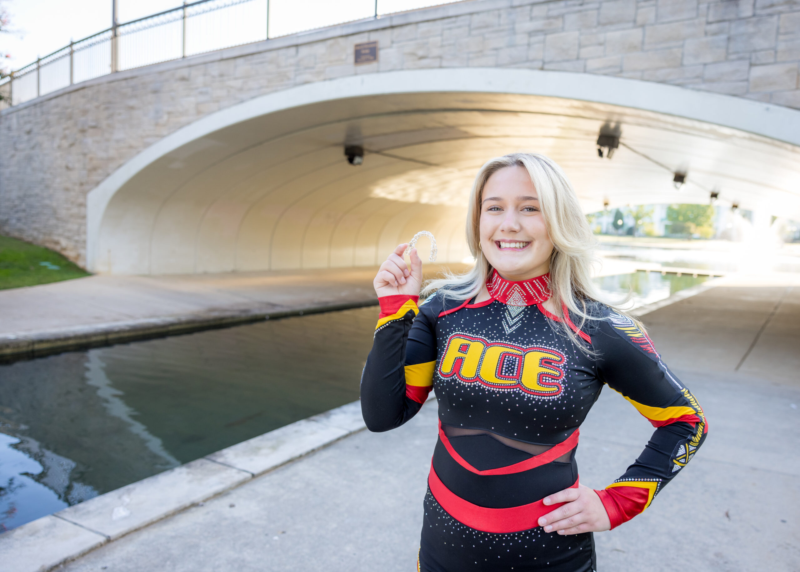 Limbaugh Orthodontics patient in her cheer uniform near a bridge