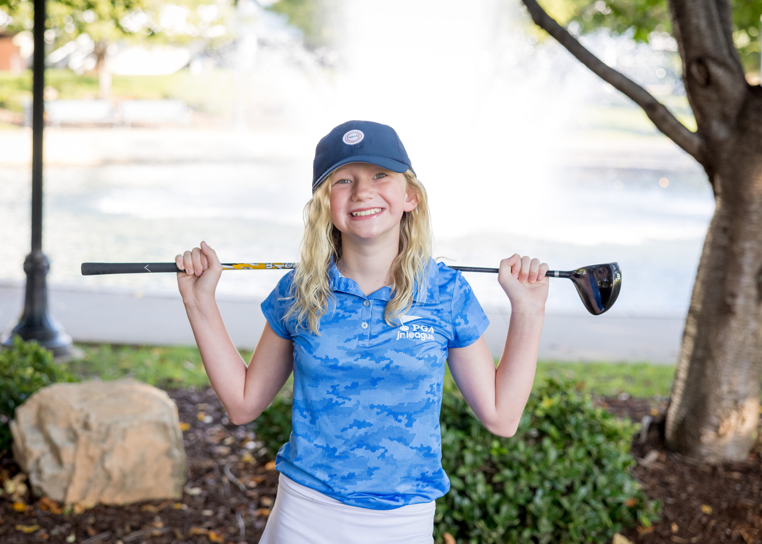 Limbaugh Orthodontics patient holding golf clubs over her shoulders