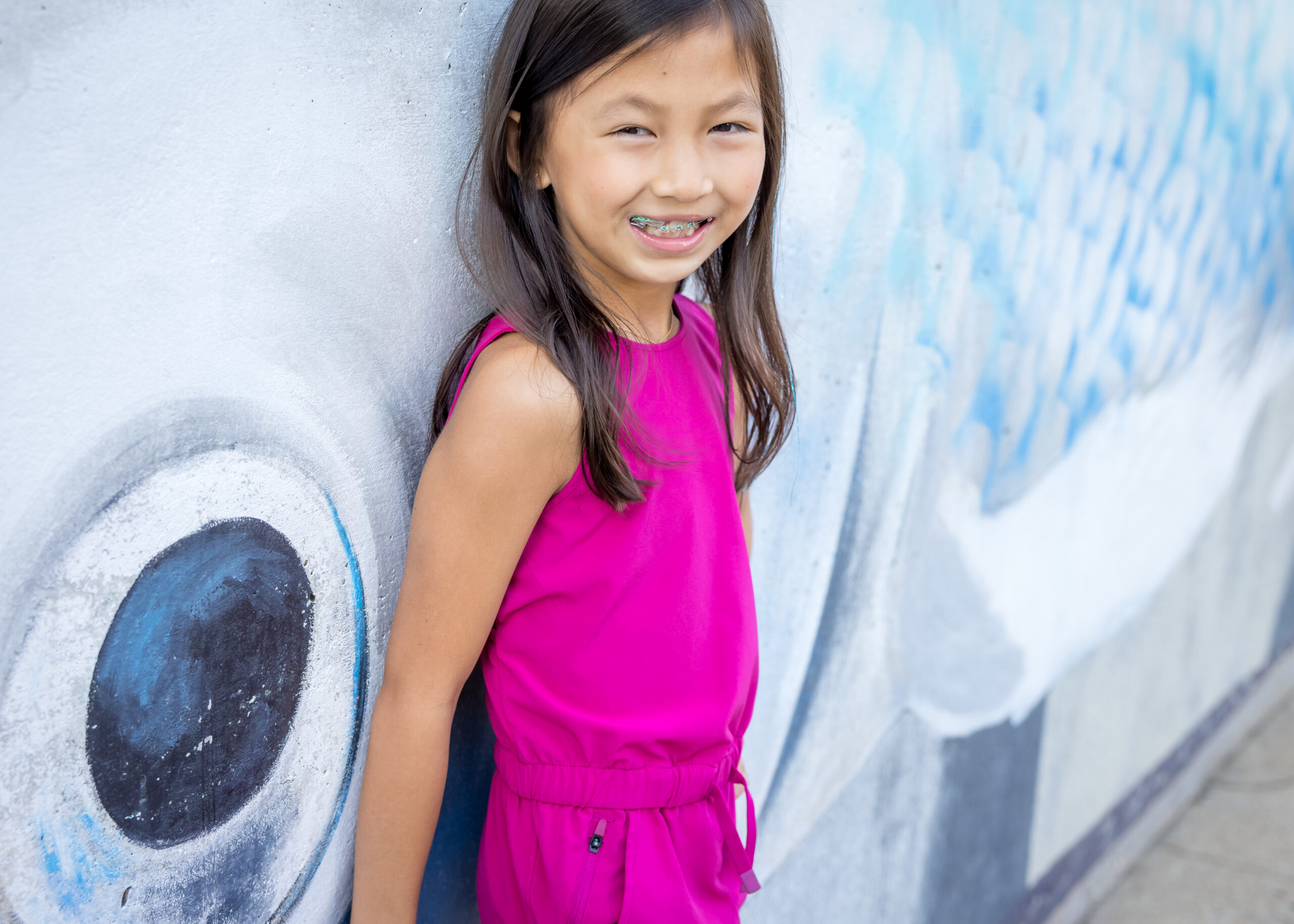 Limbaugh Orthodontics patient posing in front of a painted fish mural