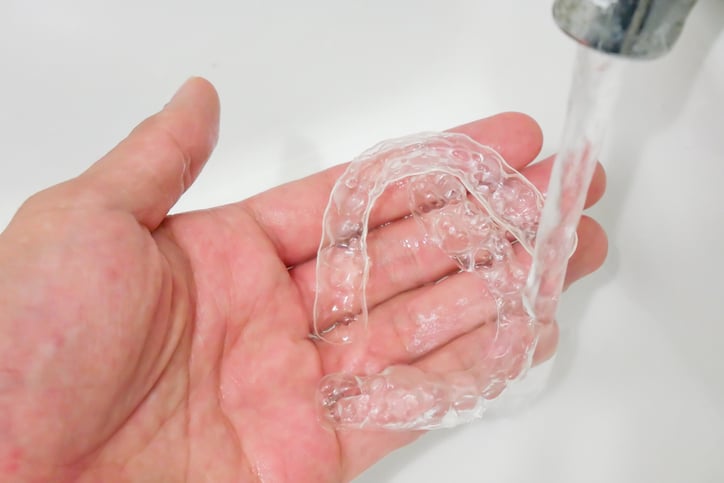 Rinsing a clear aligner under running water
