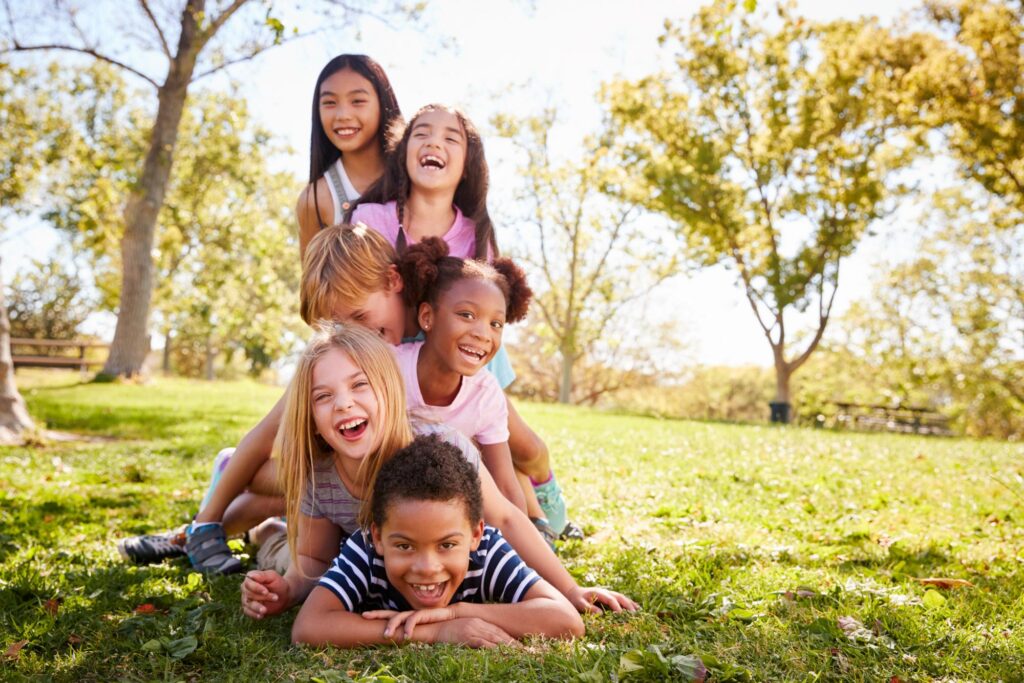 Group of children laughing together on the grass at a park