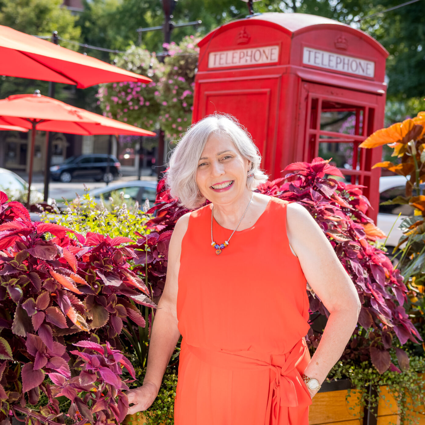 Adult Limbaugh Orthodontics patient smiling beside a red telephone booth