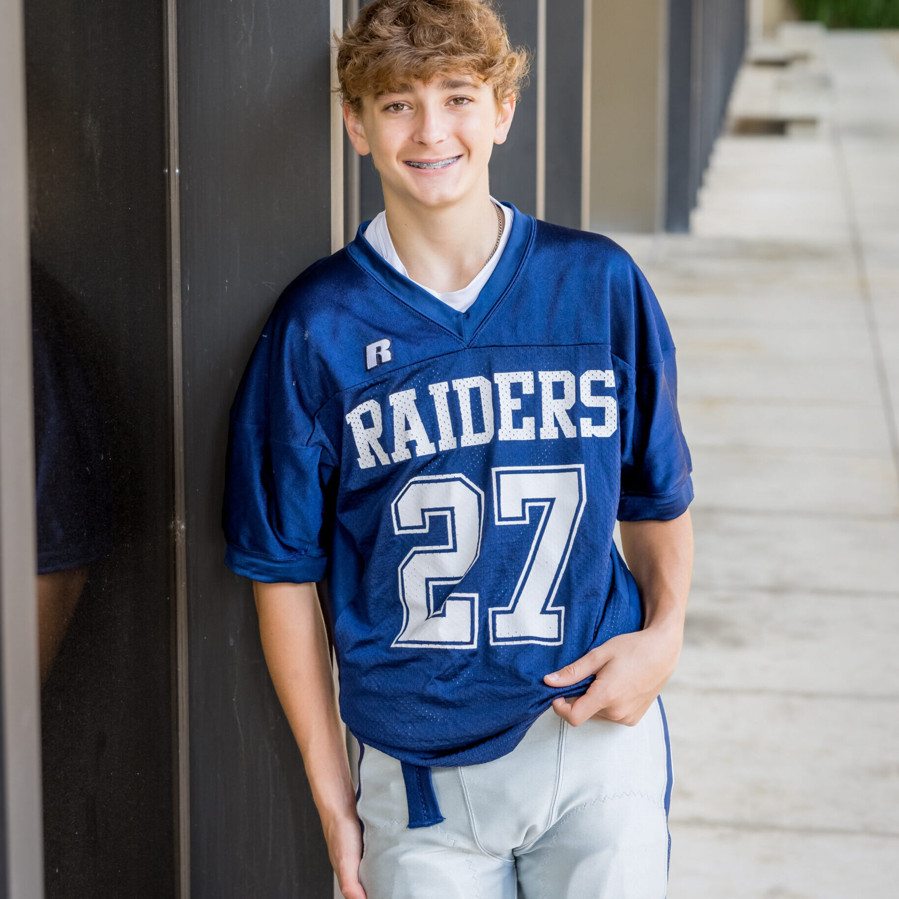 Limbaugh Orthodontics patient in his Raiders jersey against a dark wall