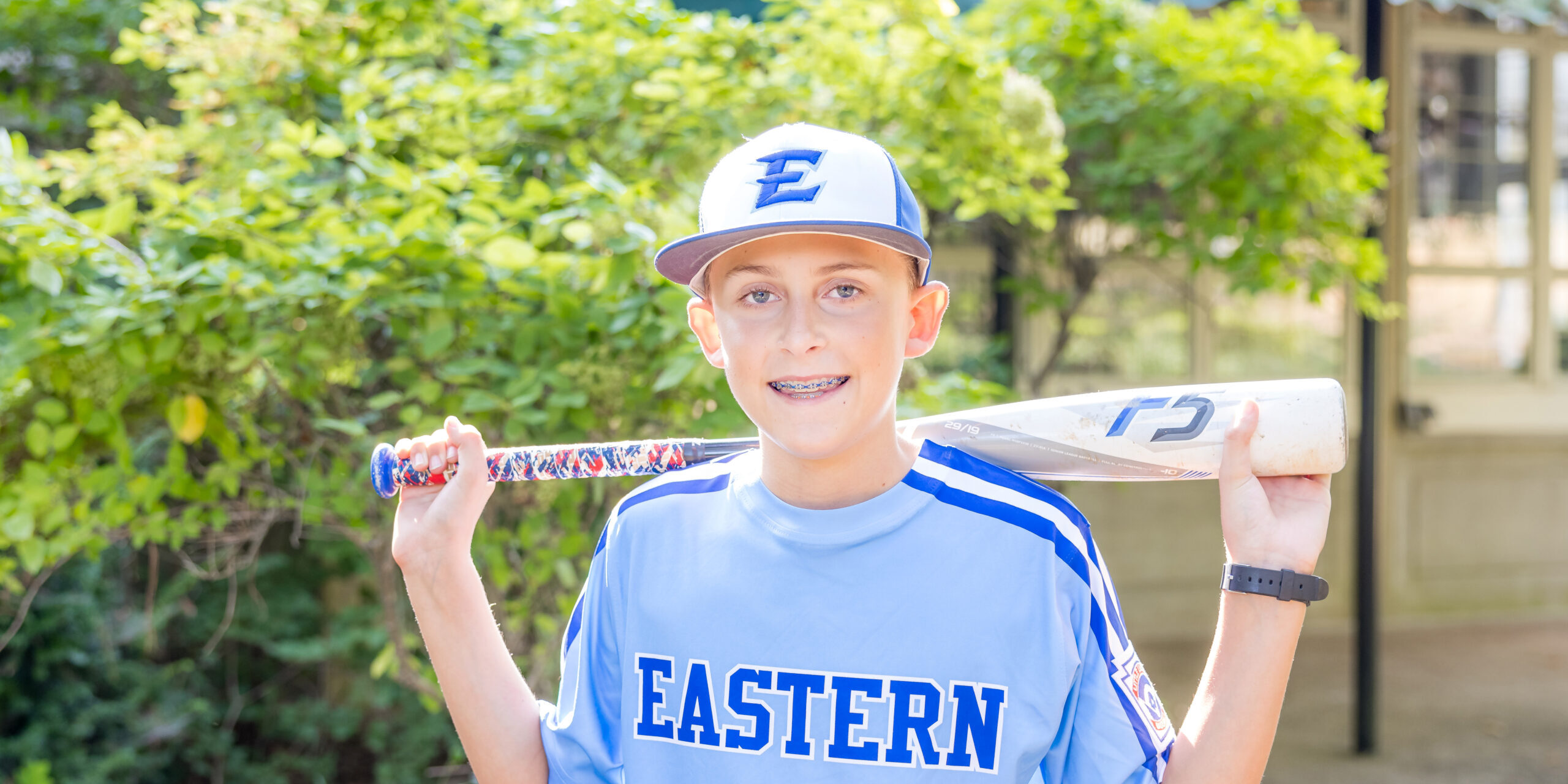 Limbaugh Orthodontics patient in his baseball uniform holding a bat