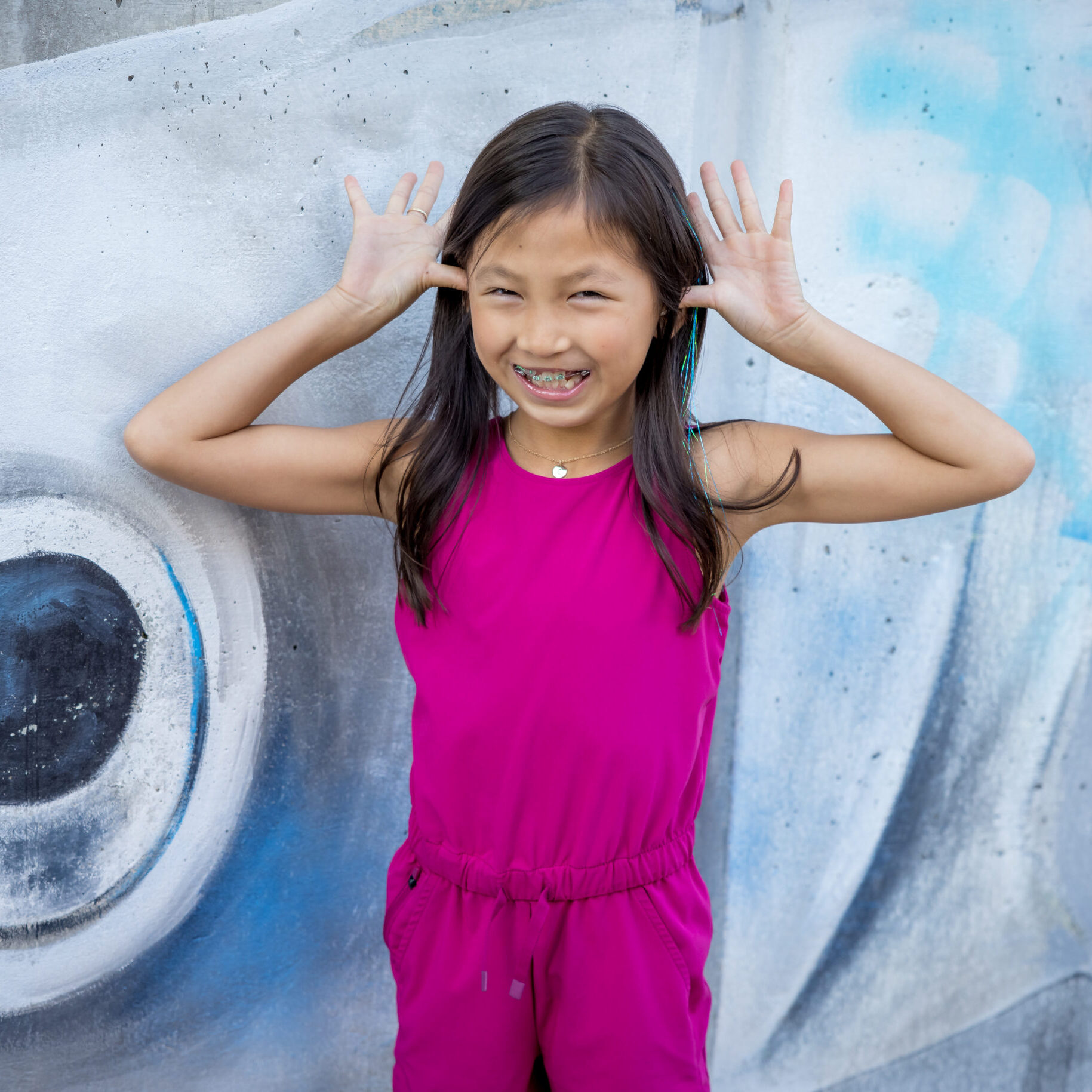 Limbaugh Orthodontics patient posing in front of a painted fish mural