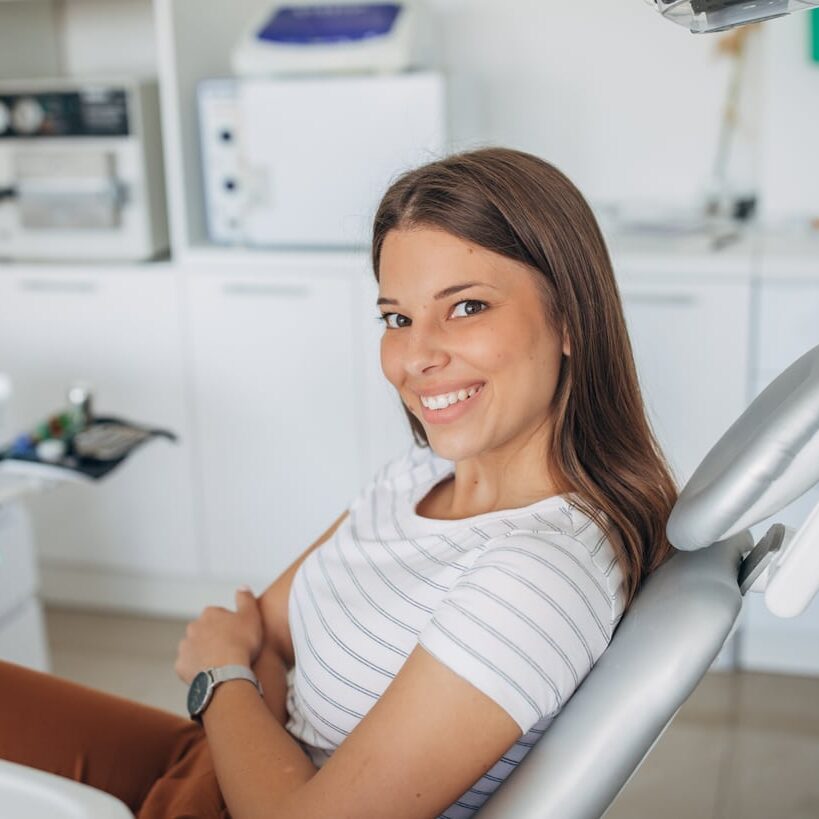 Adult patient seated in an orthodontic treatment chair and smiling
